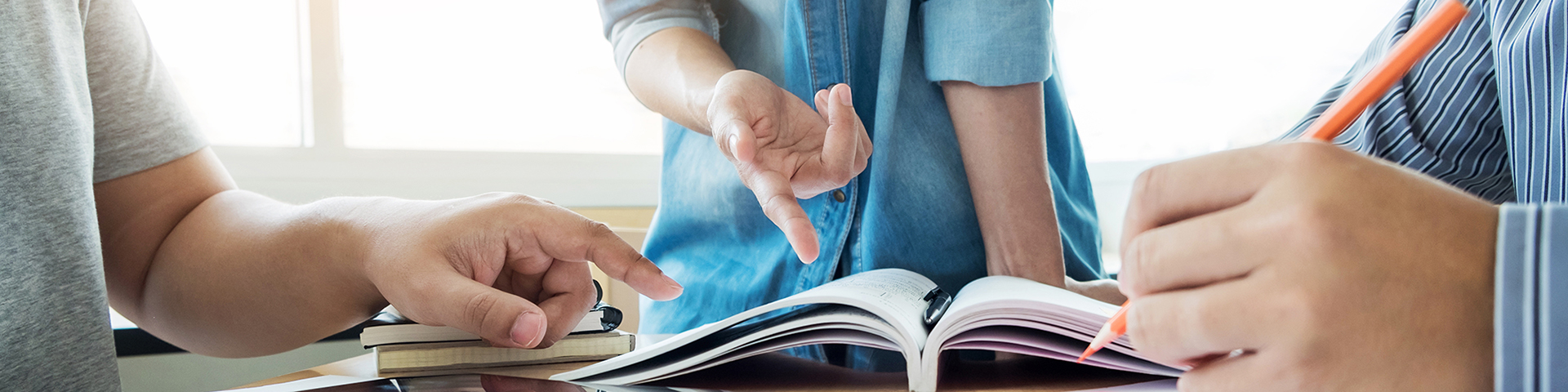 3 people collaboratively working with a book in front of them